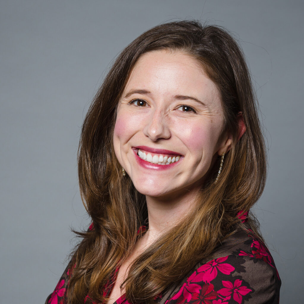 A woman in a blouse smiles at the camera