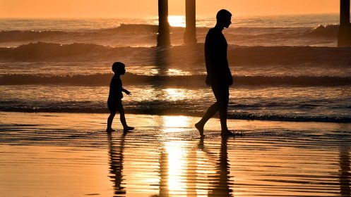 OB Pier A father and son stroll next to the Ocean Beach Pier at sunset.