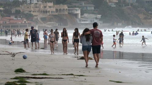 Crowds of people walk along the shoreline in La Jolla.